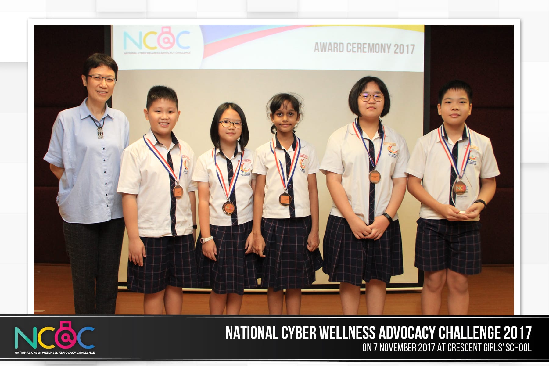 Five students wearing medals pose with a teacher at the NCAC Award Ceremony 2017 in school uniforms.